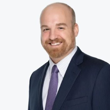 A man in a suit and tie smiling for the camera.